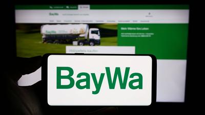 Person holding cellphone with logo of German agribusiness company BayWa AG on screen. Stuttgart, Germany - 09-14-2023: P-stock-foto