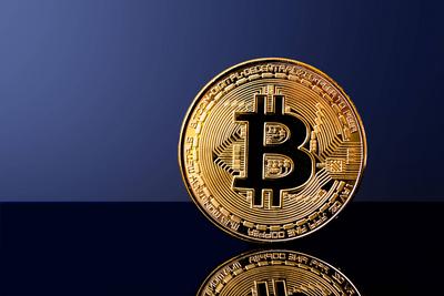 Gl?nzende Bitcoin-M?nze auf reflektierender Oberfl?che mit dunkelblauem Hintergrund-stock-foto