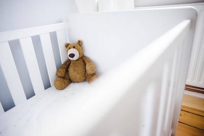 Symbolfoto zum Thema Kinderwunsch. Ein Teddybaer sitzt in einem leeren Kinderbett. Berlin, 18.01.2022 Berlin Deutschland-stock-foto