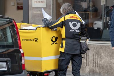 Postbotin mit gelbem Dienstfahrrad auf ihrer t?glichen Tour, M?nchen, Mai 2025-stock-foto