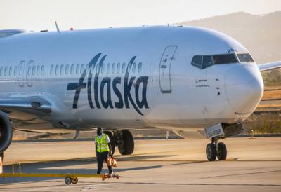 Los Cabos, B.C.S., Mexiko. 26. November 2024. Eine Boeing 737-900ER der Alaska Airlines, die an einem Flugsteig geparkt ist, w?hrend ein Mitglied des Bodenpersonals auf das Flugzeug zugeht.-stock-foto