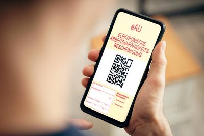 13 January 2023: Man holding smartphone with an eAU Electronic Certificate of Incapacity. Electronic sick note PHOTOMONT-stock-foto