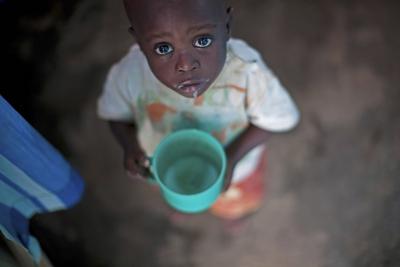 kleiner Junge mit Plastikbecher und schaut mit grossen Augen hoch in die Kamera, Burundi, Bujumbura little boy with pla-stock-foto