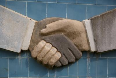 Schwarze und weisse Hand reichen sich die Hand. Wandskulptur im Aussenministerium von Benin, Cotonou, 03.01.2016. . Cot-stock-foto