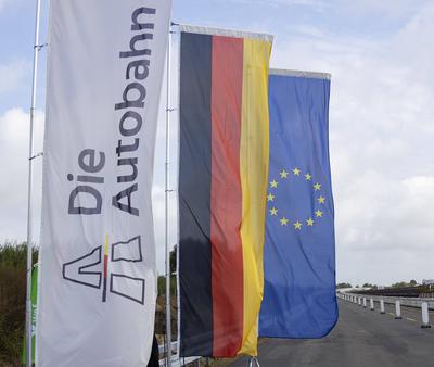 Freigabe des Neubaus der A20-Bruecke Die Fahne der Autobahn GmbH haengt neben der Deutschlandfahne und der EU-Flagge auf-stock-foto