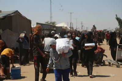 Palestinians make their way in the Mawasi area of Rafah after receiving humanitarian aid from an aid distribution point-stock-foto