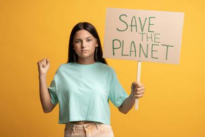 Serious zuversichtlich, brunette Teenager-M?dchen zeigt halten speichern den Planeten Plakat auf gelbem Hintergrund.-stock-foto