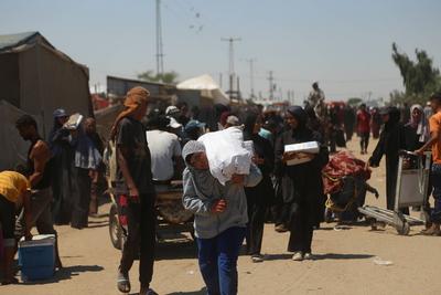 Palestinians make their way in the Mawasi area of Rafah after receiving humanitarian aid from an aid distribution point-stock-foto