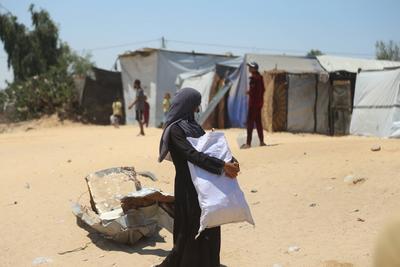 Palestinians make their way in the Mawasi area of Rafah after receiving humanitarian aid from an aid distribution point-stock-foto
