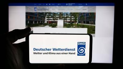 Person holding cellphone with logo of German meteorological service Deutscher Wetterdienst (DWD). Stuttgart, Germany - 0-stock-foto