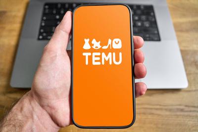 March 16, 2025: PHOTOMONTAGE, A man holds a smartphone in front of a laptop computer with the TEMU logo on the screen **-stock-foto