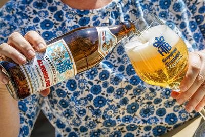 Tegernseer Hell Alkoholfrei, neues sehr gefragtes Bier des Brauhauses Tegernsee, Frau schenkt sich ein Glas Bier ein, Tegernsee, April 2025-stock-photo