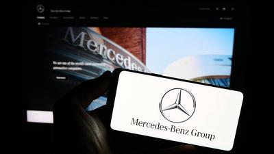 Person holding smartphone with logo of automotive company Mercedes-Benz Group AG on screen. Stuttgart, Germany - 08-20-2-stock-foto