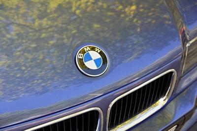Gl?nzendes BMW-Logo, das B?ume auf einem blauen Auto reflektiert-stock-foto