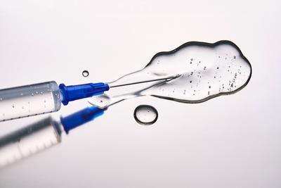 A drop of medicine flowing from a syringe with a needle. A drop of medicine flowing from a syringe with a needle. High q-stock-foto