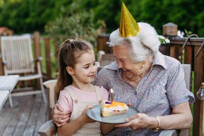 Granddaughter celebrating birthday with elderly grandma, holding cake with candle. Senior lady spending time with young-stock-foto