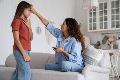 Mother checking body temperature of daughter, touching forehead. Working from home with sick child Concerned worried mot-stock-foto