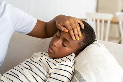 Sick ungesunde schwarze Kind kleiner Junge liegt mit geschlossenen Augen in der N?he von Mama ber?hren Stirn ?berpr?fen Temperatur-stock-foto