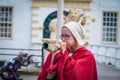 Deutschland, Dornum, Niedersachsen, Europa: Ritterfest am Wasserschloss, Frau in mittelalterlichem Gewand bl?st in ein H-stock-foto