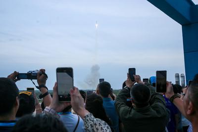 WENCHANG, CHINA - AUSGUT 04: People take photos as a Long March-12 carrier rocket carrying a group of internet satellite-stock-foto