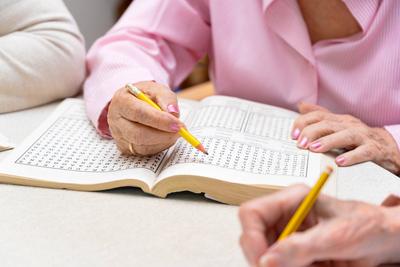 Hands of senior people solving together a word search quiz at nursing home Hands of senior people solving together a wor-stock-foto