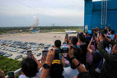 WENCHANG, CHINA - AUSGUT 04: People take photos as a Long March-12 carrier rocket carrying a group of internet satellite-stock-foto