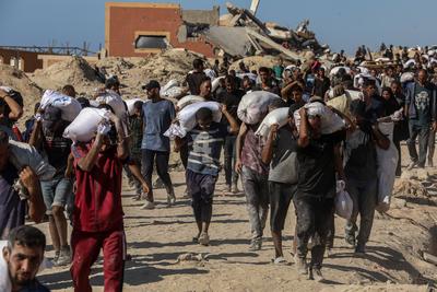 Palestinians suffering from extreme hunger under Israel intense attacks and blockade gather at an aid distribution center near the Zikim border crossing in Gaza to access limited food-stock-foto