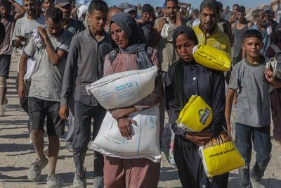 Palestinians suffering from extreme hunger under Israel intense attacks and blockade gather at an aid distribution center near the Zikim border crossing in Gaza to access limited food-stock-foto