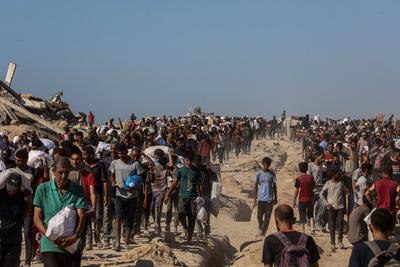Palestinians suffering from extreme hunger under Israel intense attacks and blockade gather at an aid distribution center near the Zikim border crossing in Gaza to access limited food-stock-foto