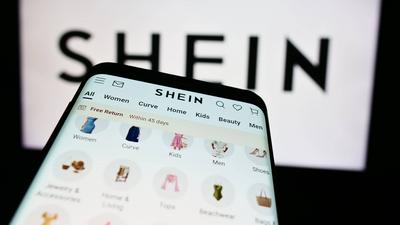 Smartphone with website of fashion e-commerce company Shein in front of business logo.-stock-foto