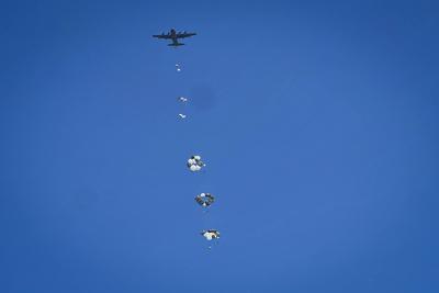 Palestinians rush to the scene as air pallets, carrying humanitarian aid, parachute down after being dropped from a military plane-stock-foto