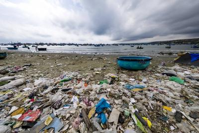 Plastic waste on the beach at Mui Ne, M? i N? , many fishing boats and storm clouds in the distance. Mui Ne Binh Thuan P-stock-foto