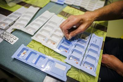 Symbolfoto zum Thema Medikamenteneinnahme im Alter. Zwei Senioren sortieren zu Hause verschiedene Tabletten zur Einnahme-stock-foto