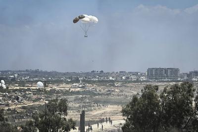 Palestinians rush to the scene as air pallets, carrying humanitarian aid, parachute down after being dropped from a military plane-stock-foto