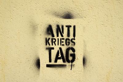 Antikriegstag, schwarzer Text mittels Spr?hschablone an eine Wand gespr?ht *** Anti-War Day, Schwarzer Text via Spray st-stock-foto