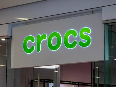 Edmonton, Alberta, Kanada. 24. Mai 2025. Das markante, gr?n beleuchtete Crocs-Logoschild signalisiert die Pr?senz der beliebten Schuhmarke und zieht mit seinem verspielten Design die Aufmerksamkeit auf sich.-stock-foto