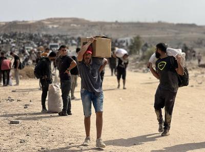 Displaced Palestinians struggling with hunger flock to an aid distribution point set up in the Netzarim Corridor in hopes of receiving limited humanitarian aid in Deir al Balah-stock-foto