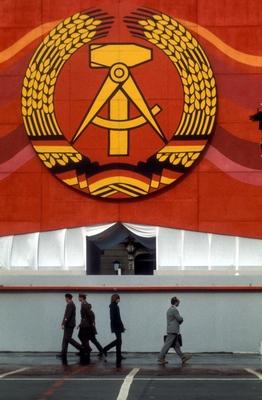 Bildnummer: 52209262  Datum: 07.10.1979  Copyright: imago/Sven SimonPassanten unter dem Emblem der DDR in Berlin Ost, Objekte , Personen , Highlight; 1979, DDR, Berlin Ost, Ostberlin, Gegensatz, Gegens?tze, Gr??enunterschied, Gr??e, Fahne, Landesfahne, Wappen, Hammer, Zirkel , Ehrenkranz; , hoch, Kbdia, Gruppenbild, Emblem, Logos, Deutsche Demokratische Republik,  , Gesellschaft; Aufnahmedatum gesch?tzt-stock-foto
