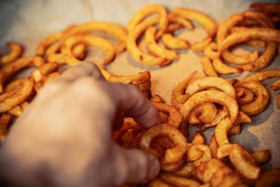 06 February 2022: curly fries from potatoes baked in an oven at home, quick unhealthy ready meal from the oven baked on-stock-foto