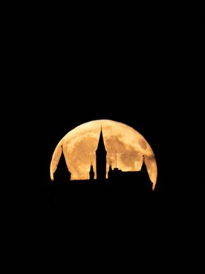 Der Vollmond geht hinter der Burg Hohenzollern am Nachthimmel auf. Die Burg ist dabei als Silhouette zu sehen. Hechingen-stock-foto