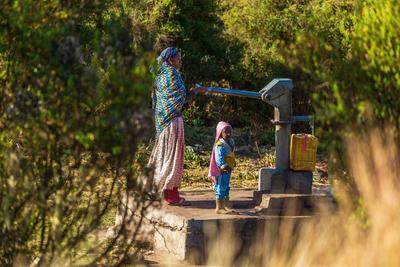 OROMIA, ETHIOPIA-JAN 21, 2019: Unidentified mother with child pumping water from a source. Mother with child pumping wat-stock-foto