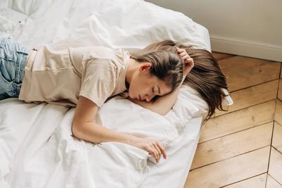 Upset sad young woman lies on the bed with her eyes closed.-stock-foto
