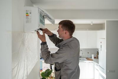 Ein Techniker repariert eine Klimaanlage in einer Wohnung-stock-foto