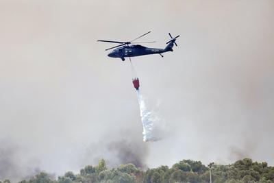 An Albanian army helicopter drops water as it fights against a wildfire raging in the town of Delvine, south-east Albani-stock-foto