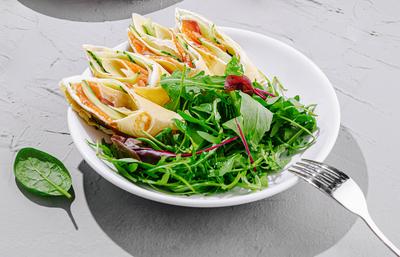 Frischer Salat und knusprige Snacks, serviert auf einem grauen Tisch mit gr?nem Laub im Hintergrund w?hrend der Tageszeit-stock-foto