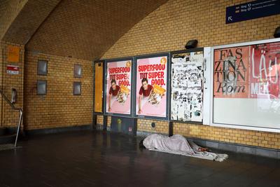 Obdachloser, sp?rlich bekleidet und barfu?, schl?ft auf seinem kargen Lager, bestehend aus zwei Decken auf dem kalten Fl-stock-foto