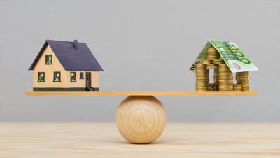 Baufinanzierung Auf einer Wippe ist ein Modellhaus und die symbolische Finanzierung im Gleichgewicht - FOTOMONTAGE *** C-stock-foto
