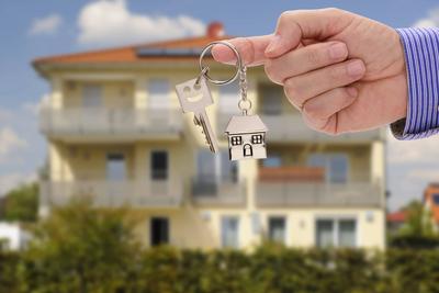 Schl?ssel zu einem Eigenheim Eine Hand h?lt einen Wohnungsschl?ssel vor einem neugebauten Haus als Symbol f?r ein Eigenh-stock-foto