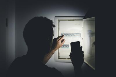 Bavaria, Germany - 25 September 2022: Power failure in the apartment, man shines the flashlight in his smartphone in th-stock-foto