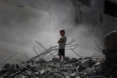 Palestinians walk through the rubble of the Tiba tower which crashed to the ground moments after Israeli strikes-stock-foto